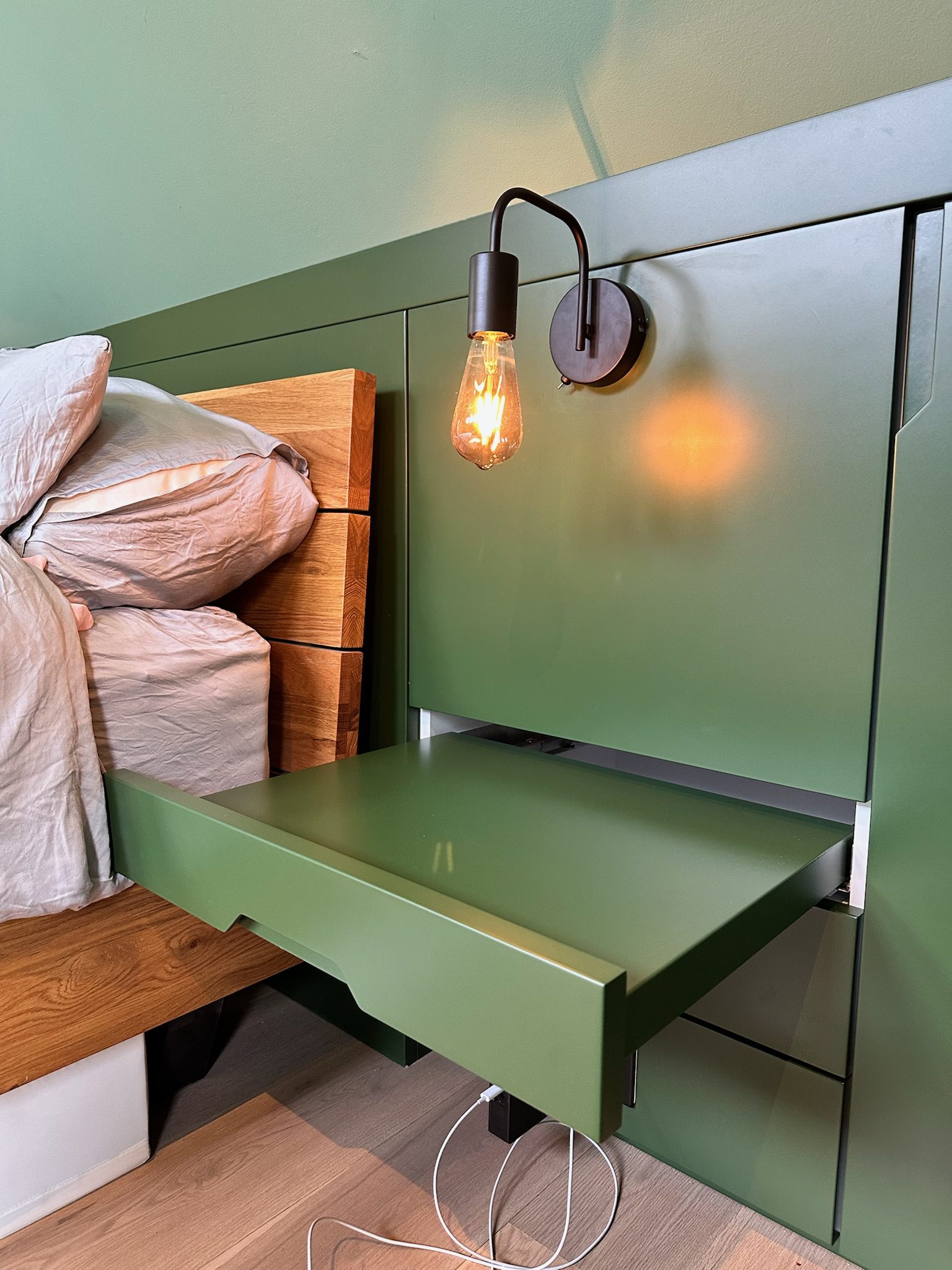 Green sliding side table next to bed